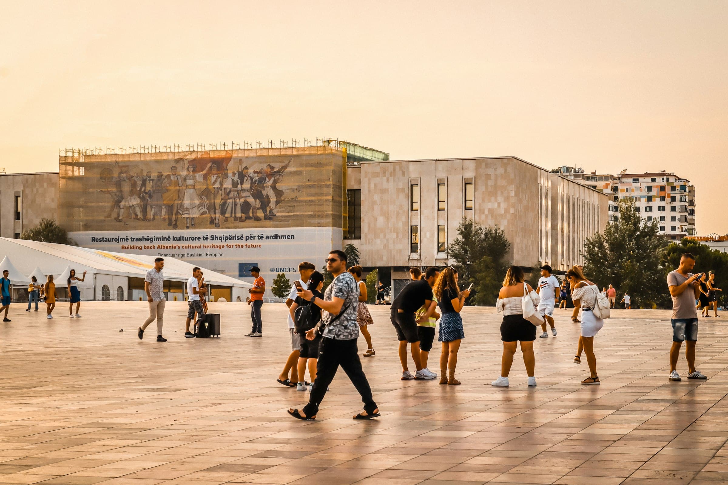 People crossing Skanderbeg Square in Tirana in warm evening light