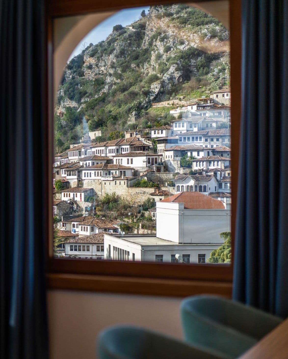 An arched window in Merko Hotel looking out over the white houses of Berat