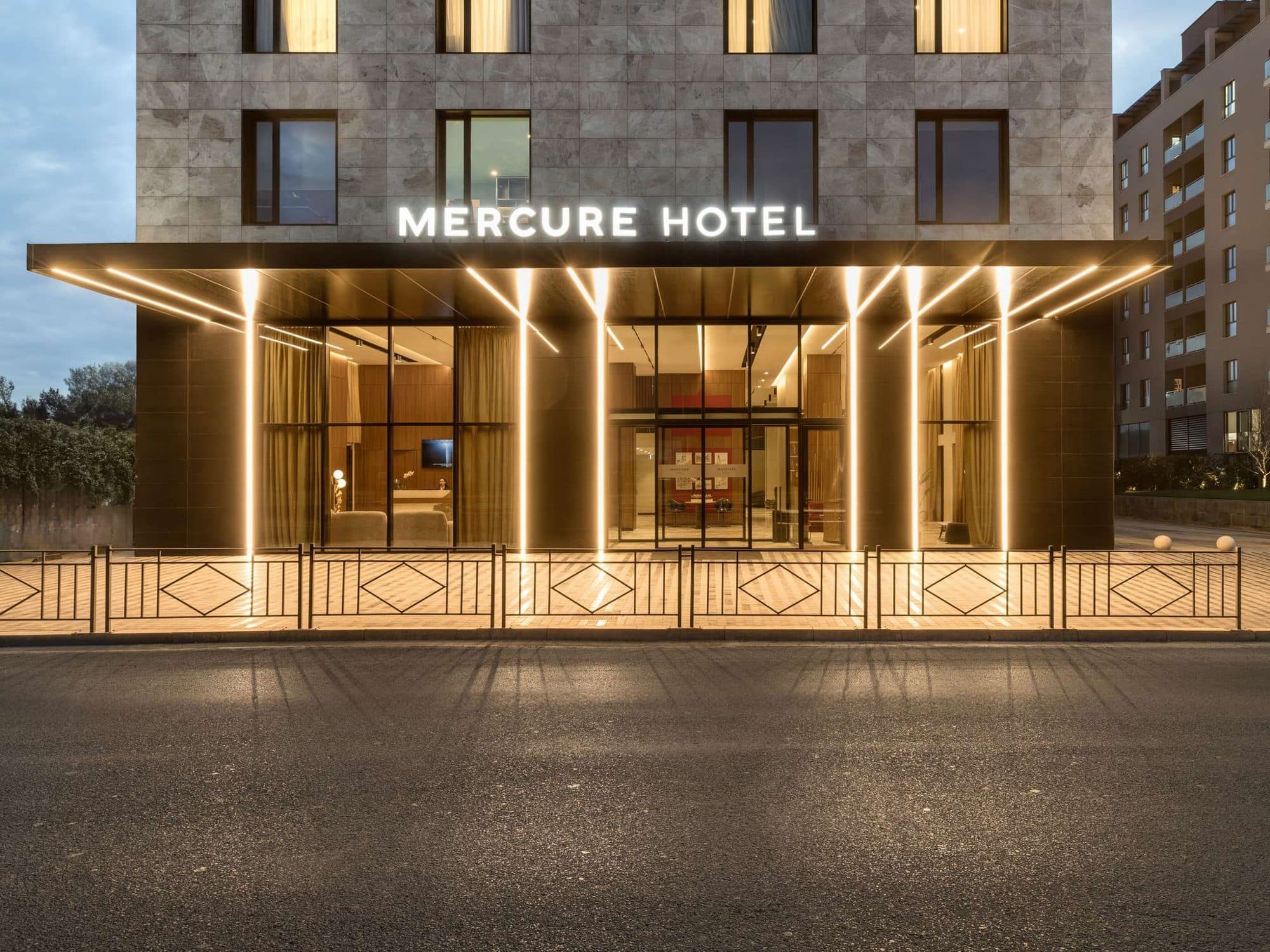 The lit entrance of Mercure Tirana at dusk